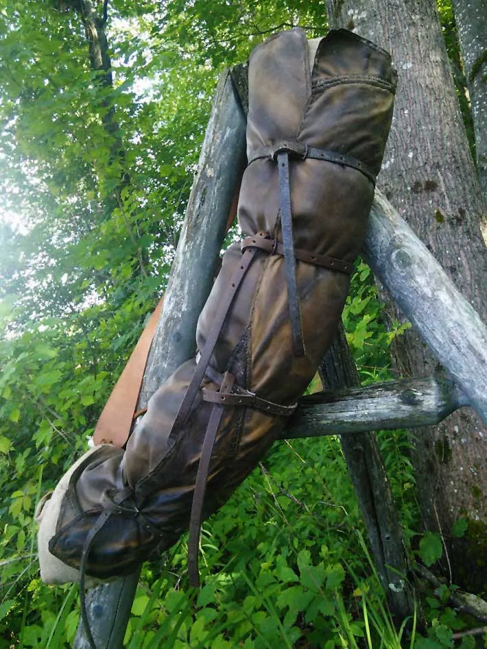 A rolled goatskin bedroll cover leaning on a fallen log in green woods